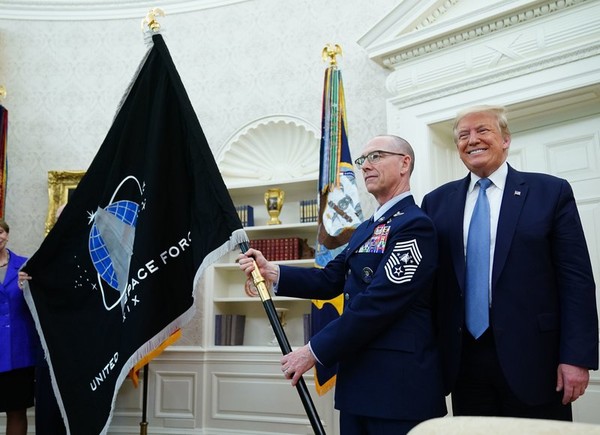 도널드 트럼프 미국 대통령이 15일 백악관 집무실에서 우주군기를 수여하고 포즈를 취하고 있다. 사진=NPR