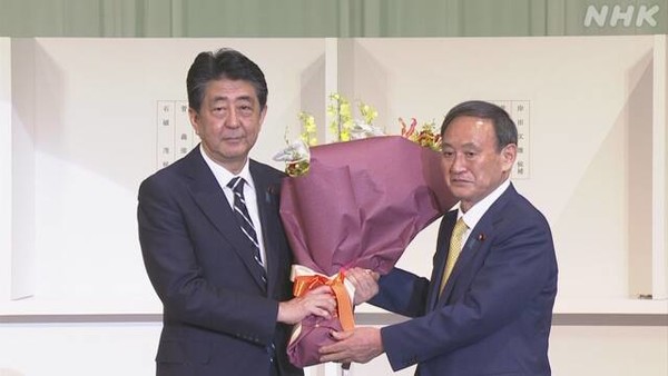 아베 신조 일본 전 총리와 스가 요시히데 일본 자민당 총재 당선자가 꽃다발을 들고 포즈를 취하고 있다. 사진=NHK방송