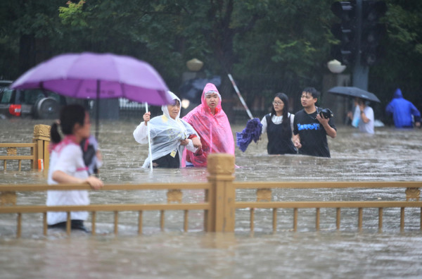 폭우가 쏟아진 20일 중국 허난성 정저우시에서 시민들이 허리까지 찬 물속을 걸어 안전한 곳으로 피하고 있다.사진=차이나데일리